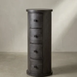 Dreiviertelansicht des zylinderförmigen Beistellschranks aus massivem Mangoholz, der die Tiefe der geschwungenen Schubladen und die schlanke Silhouette hervorhebt._#sku_SAFWL6.842#